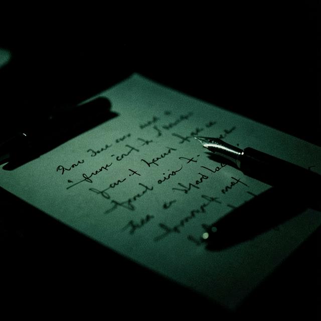 Fountain pen resting on handwritten paper in low light