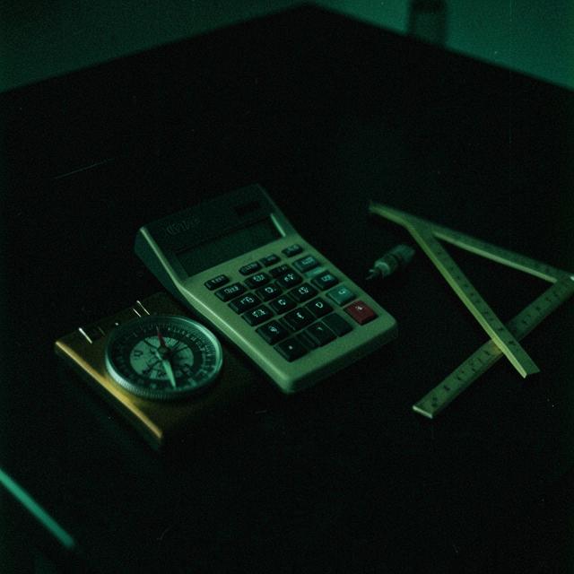 Dark desk with a calculator, compass and set square